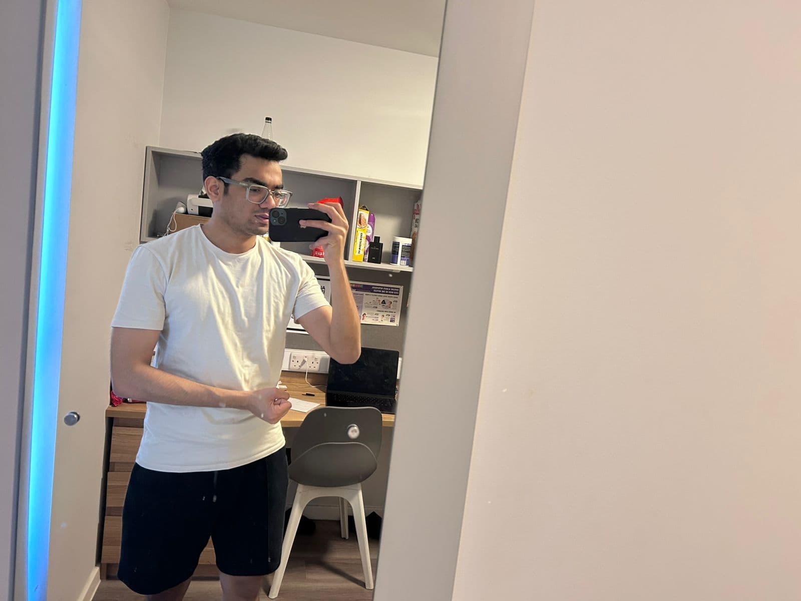 Kshitiz taking a mirror selfie in a white t-shirt